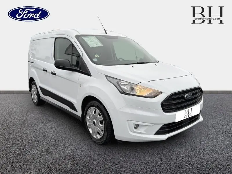 Vue 3/4 avant droit du Ford Transit Connect L1 blanc glacier avec phares allumés et protections latérales noires.