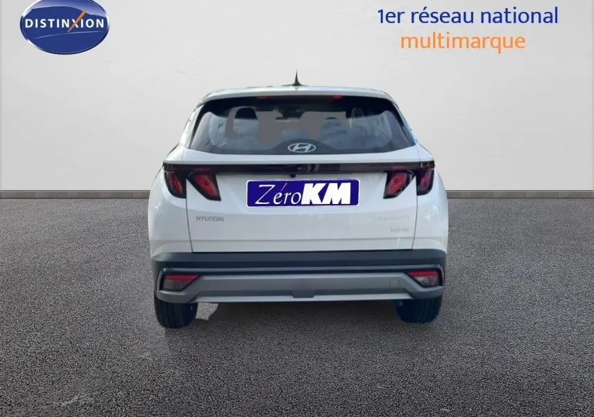 Vue arrière d'un Hyundai Tucson blanc Atlas 2026 avec feux arrière noirs et logo Hyundai visible.