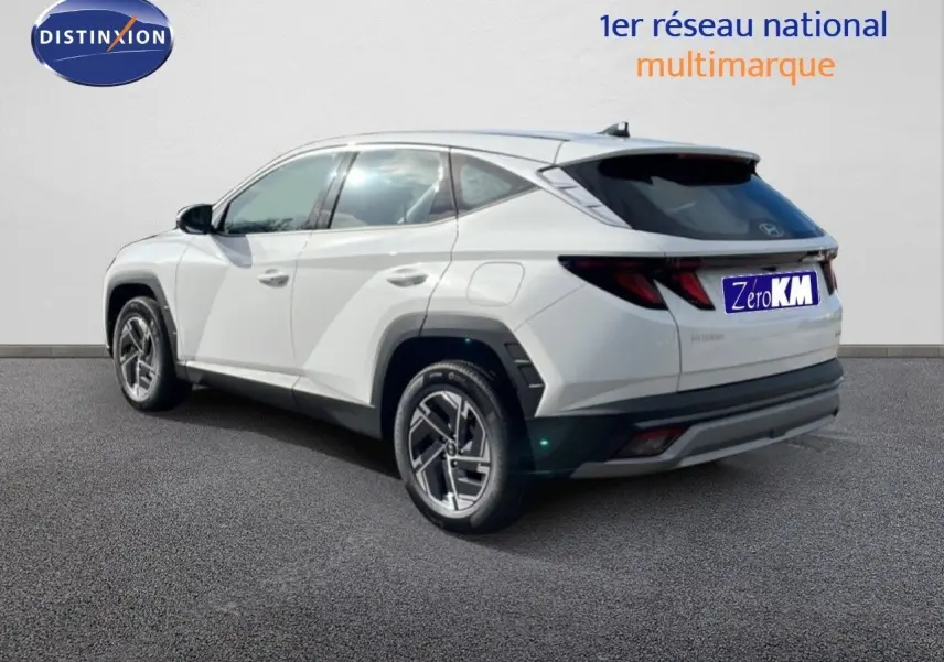 Vue 3/4 arrière droite du Hyundai Tucson blanc Atlas 2026 avec jantes bi-ton et vitres teintées.