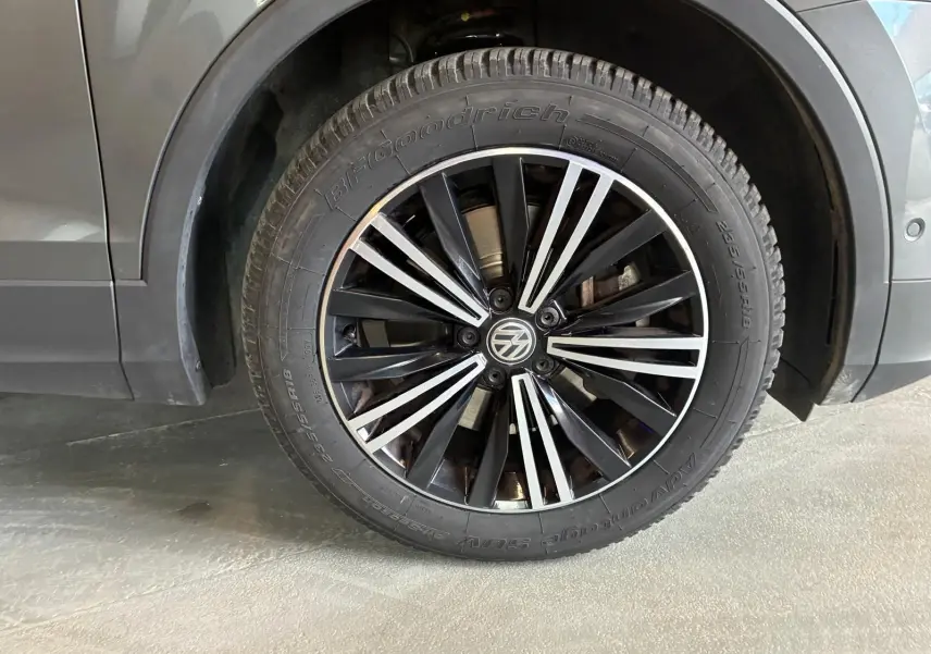 Gros plan sur la roue avant gauche d’un Volkswagen Tiguan gris, avec jante noire et argentée au design moderne.