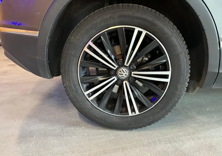 Gros plan sur la roue avant droite du Volkswagen Tiguan gris, mettant en valeur la jante noire et argentée au design moderne.