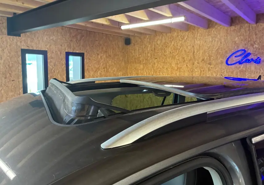 Toit ouvrant ouvert vu de près sur le côté gauche d’un Volkswagen Tiguan gris dans un garage.