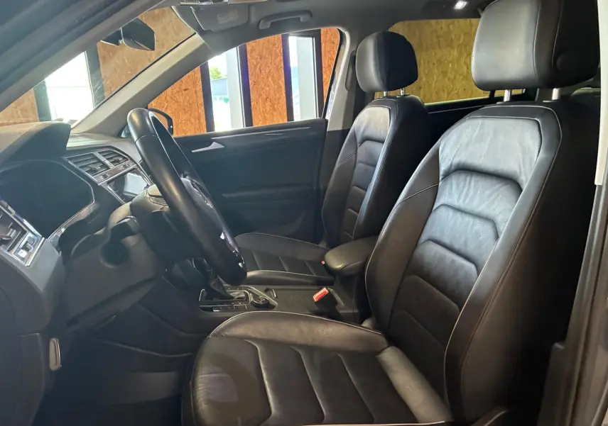 Vue intérieure côté conducteur du Volkswagen Tiguan 2020, sièges en cuir noir et tableau de bord moderne.