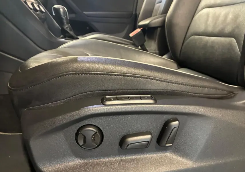Gros plan sur le siège conducteur en cuir noir d’un Volkswagen Tiguan 2020, avec commandes électriques visibles sur le côté.