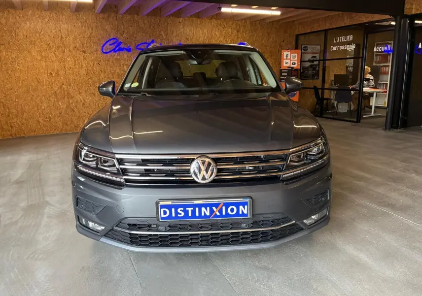 Vue avant d'un Volkswagen Tiguan gris 2020, avec calandre chromée et phares LED, en intérieur showroom.