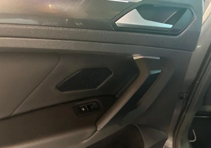 Détail de la porte intérieure côté gauche du Volkswagen Tiguan 2020 gris, avec poignée et commande de vitre.