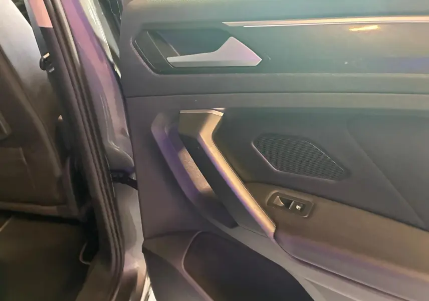 Détail de la porte arrière gauche grise d’un Volkswagen Tiguan 2020 avec poignée et commande de fenêtre.