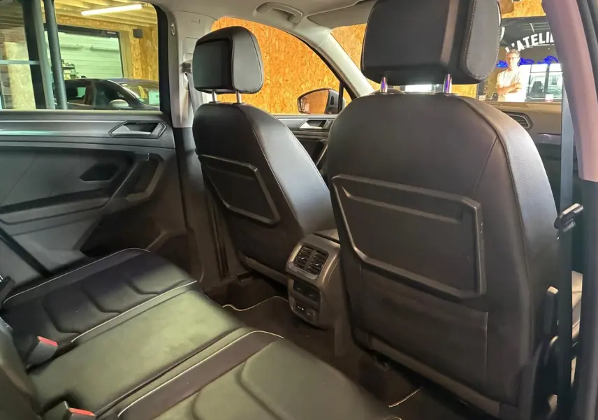 Vue intérieure arrière du Volkswagen Tiguan 2020, sièges en cuir noir et aérateurs centraux visibles.