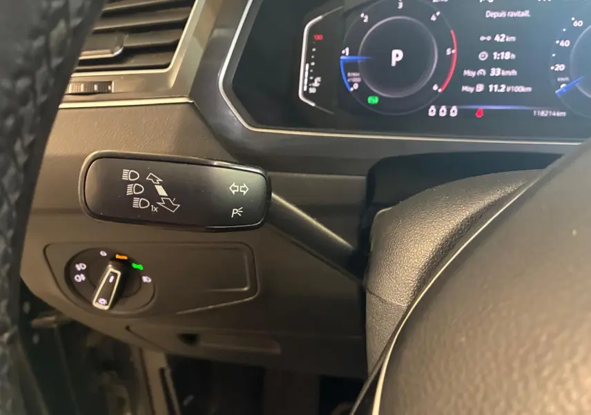 Détail intérieur du Volkswagen Tiguan 2020 montrant le commodo des clignotants et le tableau de bord numérique en arrière-plan.