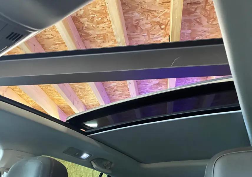Vue intérieure du toit ouvrant panoramique ouvert du Volkswagen Tiguan gris, montrant la structure du plafond en bois.