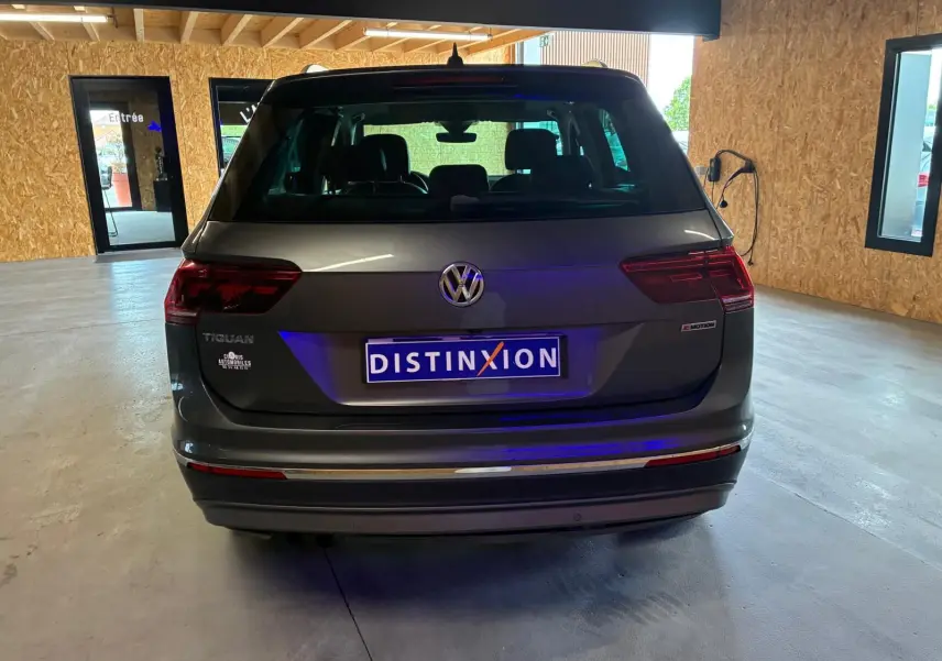 Vue arrière d'un Volkswagen Tiguan gris 2020 avec logo 4MOTION dans un garage lumineux.