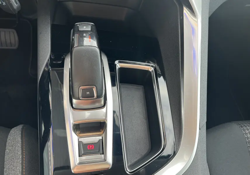 Vue rapprochée de la console centrale noire et argentée du Peugeot 3008 blanc, avec levier de boîte automatique et frein à main électronique.
