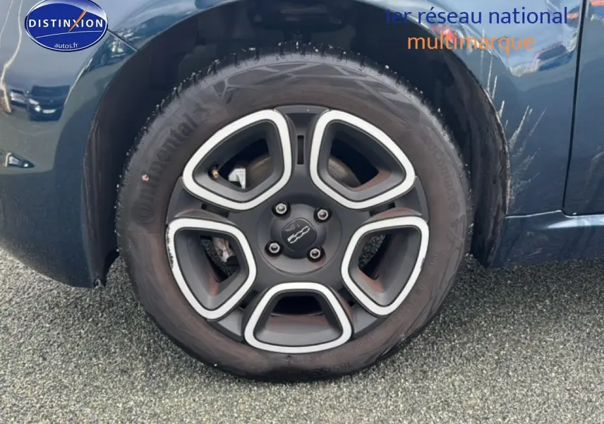 Gros plan sur la roue avant droite d'une FIAT 500 bleu foncé, avec jante noire et argentée au design distinctif.