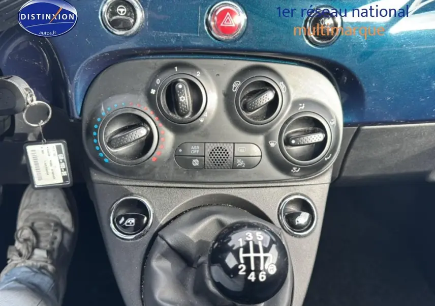 Vue rapprochée du levier de vitesses manuel et des commandes de climatisation sur tableau de bord bleu foncé d’une Fiat 500.