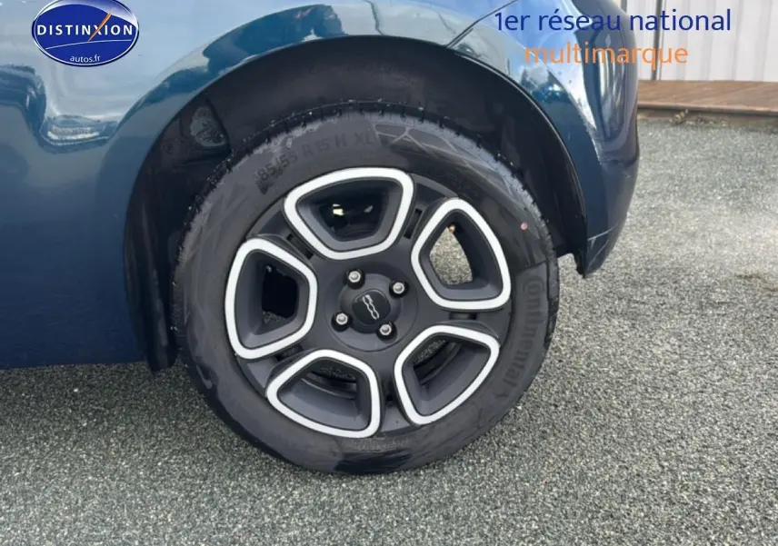 Gros plan sur la roue arrière droite d'une Fiat 500 bleu foncé avec jante au design moderne.