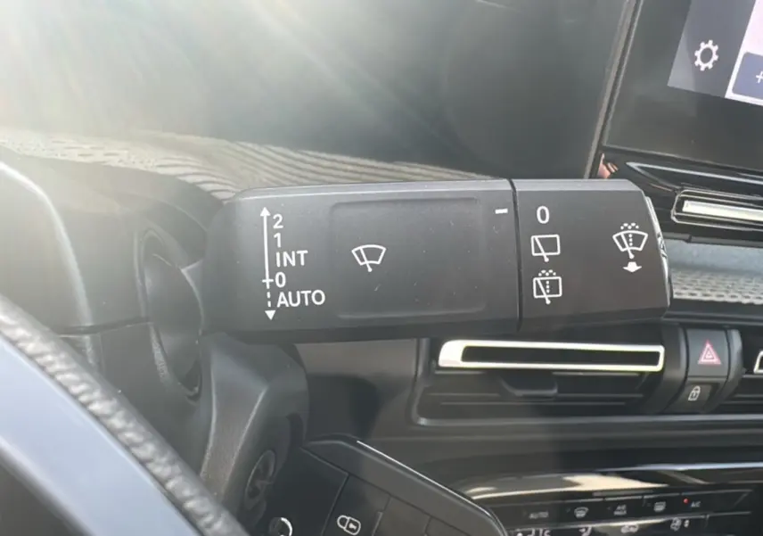 Gros plan sur la commande d’essuie-glace à gauche du volant dans l’habitacle sombre d’une Citroën C3 Aircross 2025.