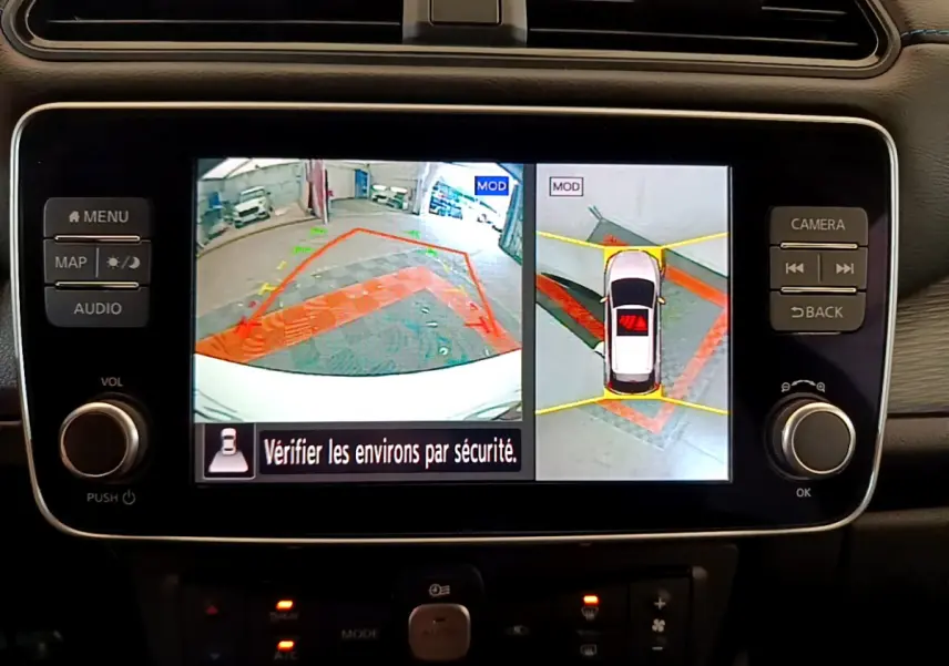Écran tactile central de la Nissan Leaf blanche 2020 affichant la caméra 360° et l'aide au stationnement en vue arrière.