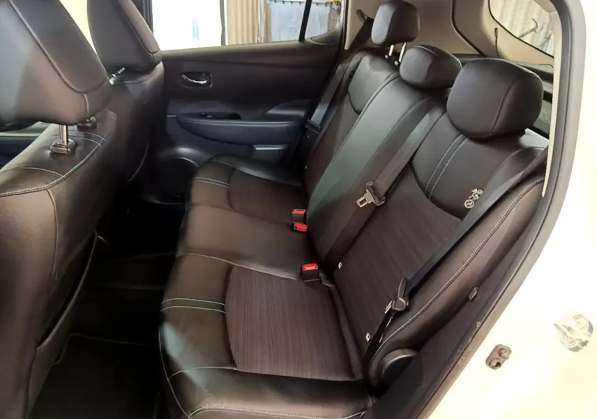 Vue intérieure côté droit sur la banquette arrière noire avec surpiqûres bleues du Nissan Leaf blanc 2020 Business+.