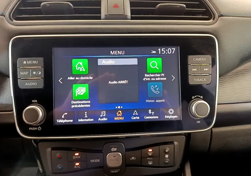 Écran tactile central allumé du système multimédia d'une Nissan Leaf blanche 2020, vue intérieure frontale.