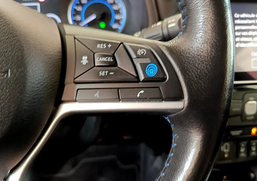Gros plan sur le côté gauche du volant cuir noir de la Nissan Leaf 62 kWh 2020, avec commandes de régulateur adaptatif.