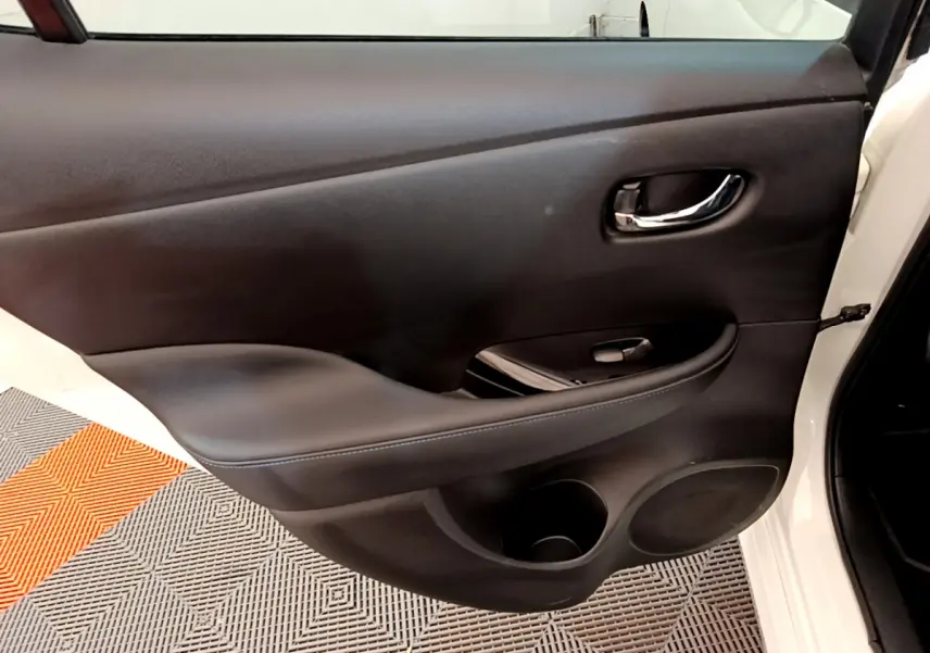 Vue rapprochée de la porte arrière droite noire intérieure d'une Nissan Leaf blanche 2020 avec poignée chromée.