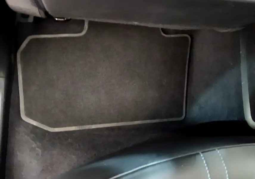 Vue rapprochée du tapis de sol noir et du bas du siège avant dans une Nissan Leaf blanche de 2020.