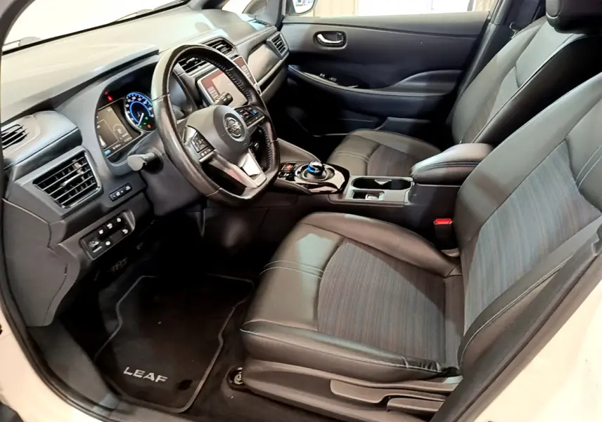 Intérieur avant droit de la Nissan Leaf blanche 2020, volant cuir multifonctions et sièges noirs en tissu et cuir.