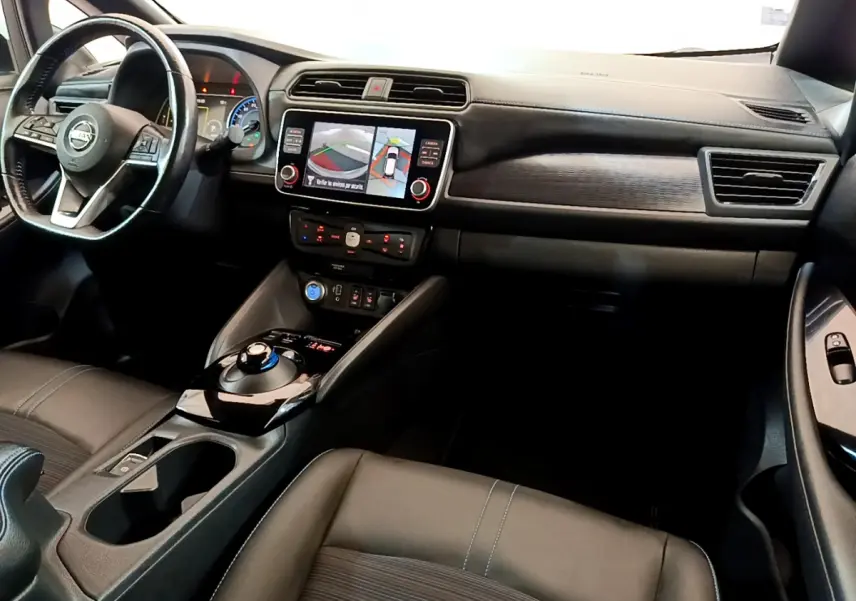 Vue intérieure côté conducteur du tableau de bord noir du Nissan Leaf 62 kWh avec écran tactile et volant cuir multifonctions.