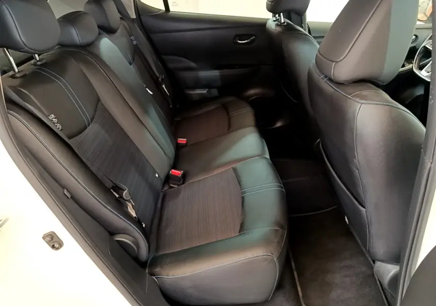 Vue côté gauche de l'habitacle arrière d'une Nissan Leaf blanche, sièges noirs avec surpiqûres bleues.