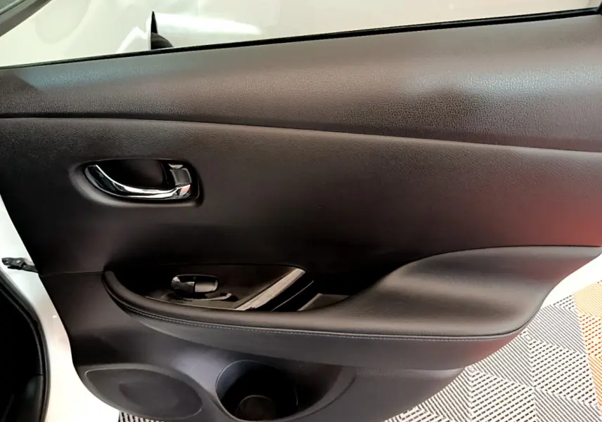 Gros plan sur la porte intérieure côté conducteur noire du Nissan Leaf blanc 2020, avec poignée chromée et commande de vitre.