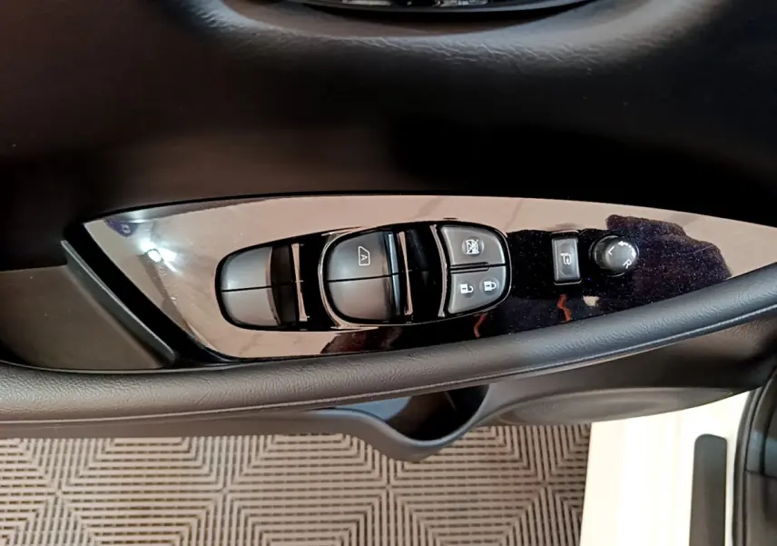 Gros plan sur les commandes de lève-vitres et réglages des rétroviseurs côté conducteur du Nissan Leaf blanc 2020.