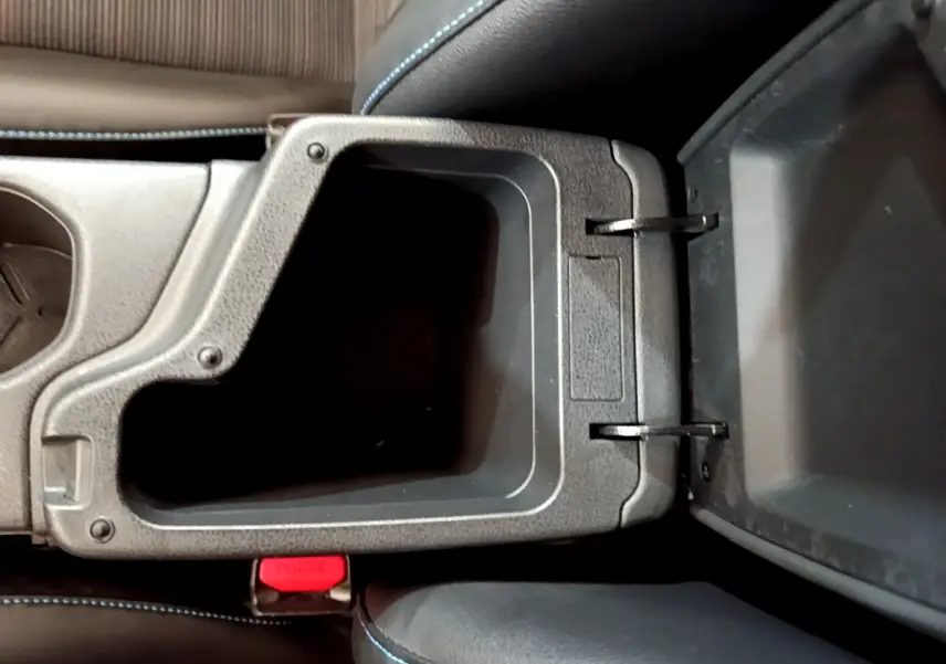 Vue plongeante sur le rangement central ouvert avec coutures bleues, intérieur noir de la Nissan Leaf blanche 2020.