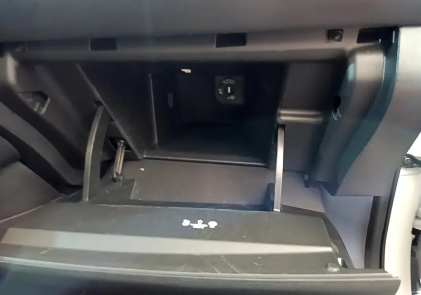 Gros plan sur la boîte à gants ouverte du Nissan Leaf blanc 2020, montrant une prise 12V à l'intérieur.