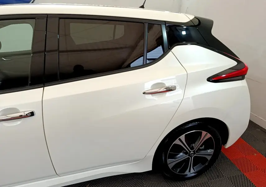 Vue côté droit arrière du Nissan Leaf blanc 62 kWh avec vitres teintées et feux arrière distinctifs en forme de boomerang.