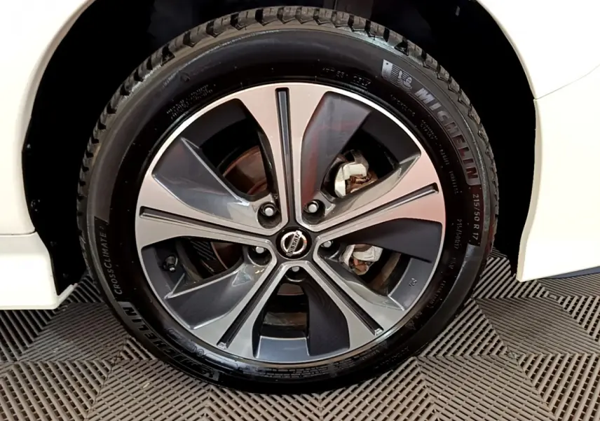Gros plan sur la roue avant droite d'une Nissan Leaf blanche, jante alliage bicolore et pneu Michelin visible.