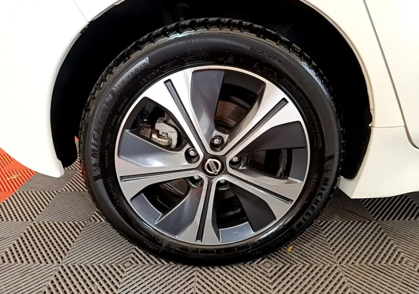 Gros plan sur la roue avant droite avec jante alliage bicolore du Nissan Leaf blanc 2020 électrique.