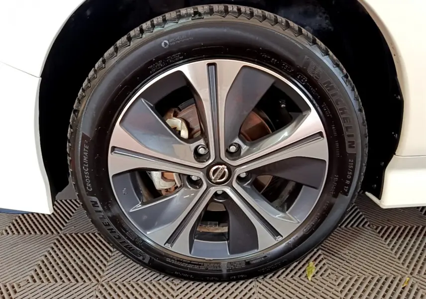 Gros plan sur la roue avant droite d'une Nissan Leaf blanche, jante alliage à cinq branches doubles et pneu Michelin.