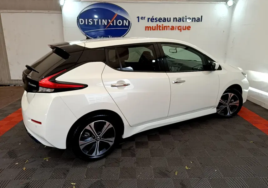 Vue côté droit d'une Nissan Leaf blanche 2020 avec toit noir, feux arrière en forme de boomerang et jantes stylisées.