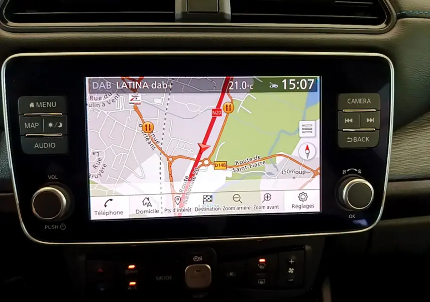 Écran tactile central du tableau de bord du Nissan Leaf blanc 2020 affichant la navigation GPS en plein jour.