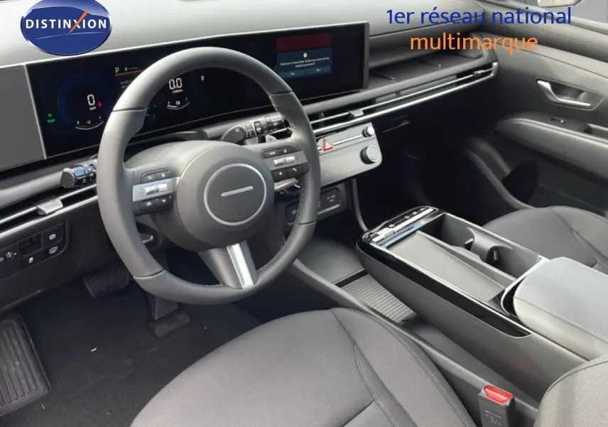 Vue intérieure côté conducteur du Hyundai Tucson 2026, tableau de bord et volant multifonction en noir avec sièges tissu.