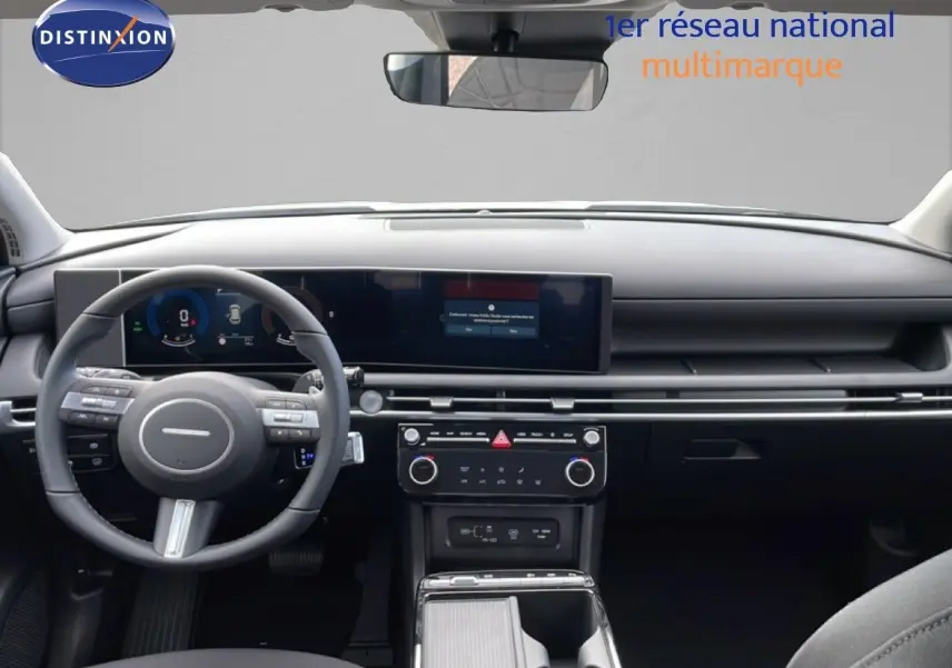 Vue intérieure avant du Hyundai Tucson 2026 avec tableau de bord noir et écran tactile panoramique.