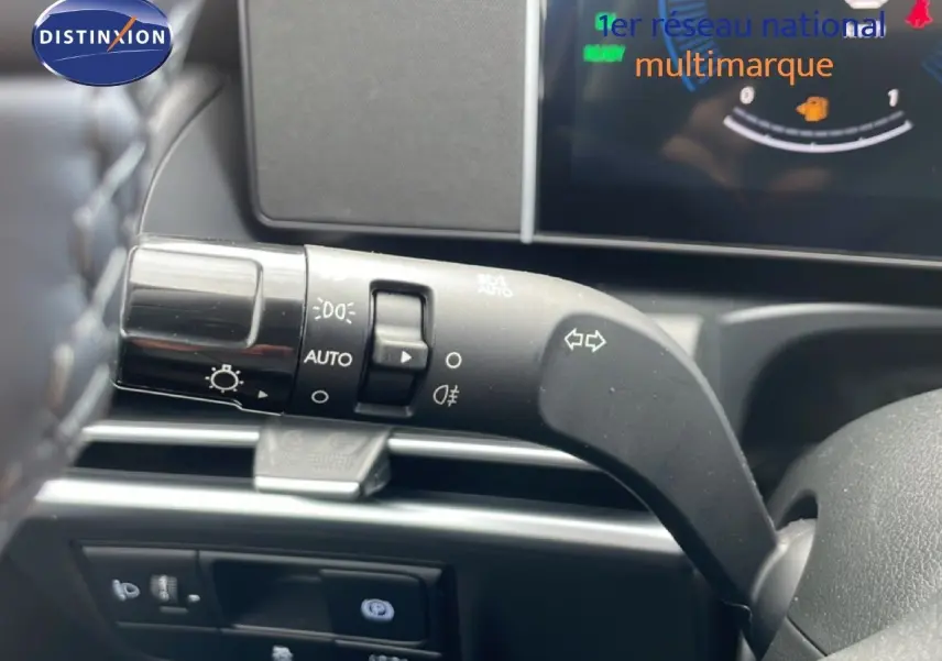 Gros plan sur la commande des feux et clignotants à gauche du volant dans l’habitacle du Hyundai Tucson blanc.