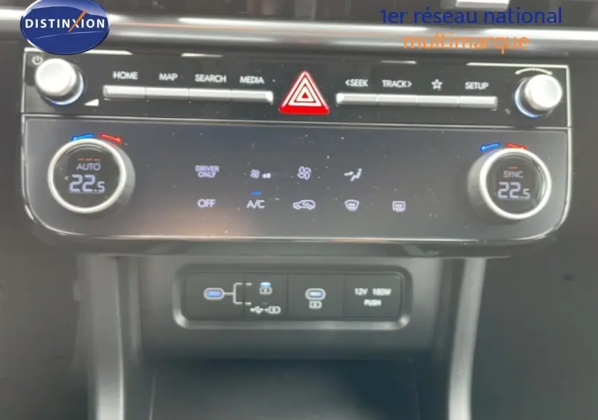 Vue rapprochée de la console centrale du Hyundai Tucson blanc Atlas 2026, avec commandes climatisation et ports USB visibles.