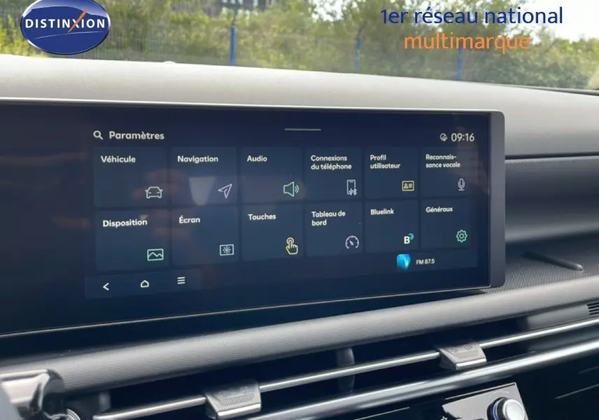 Écran tactile central affichant le menu paramètres dans l’habitacle du Hyundai Tucson blanc, vue de face.