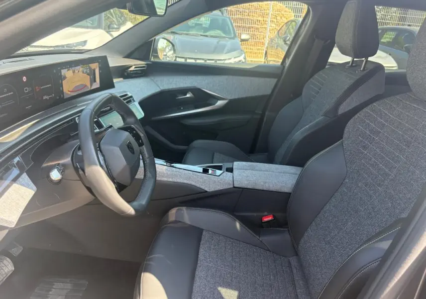 Vue intérieure côté conducteur du Peugeot 3008 Hybrid 145 e-DCS6 Allure 2025, sièges gris et tableau de bord numérique.
