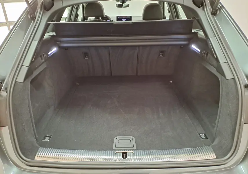 Coffre ouvert de l'Audi A4 Avant 40 TDI gris Daytona, vue arrière montrant l'espace de chargement et la finition intérieure noire.