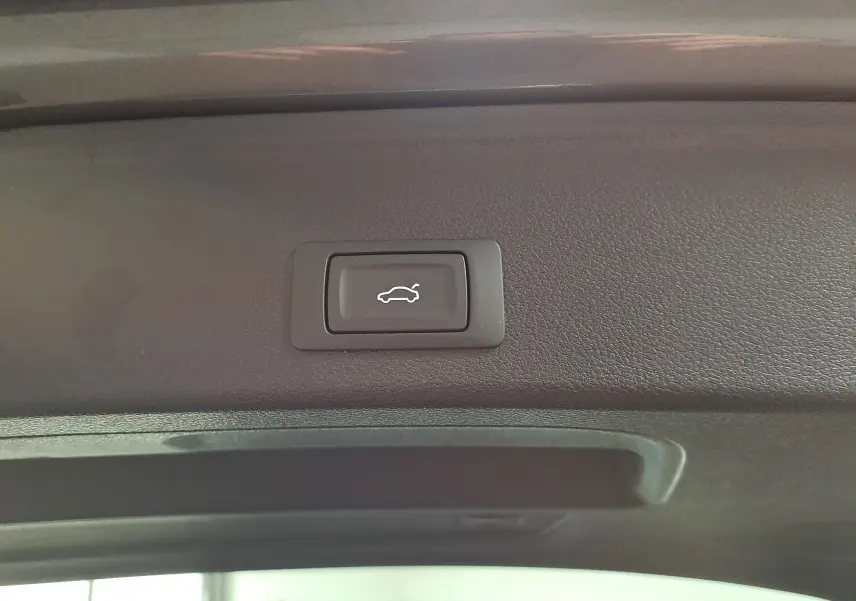 Bouton d'ouverture électrique du hayon sur le bord intérieur du coffre d'une Audi A4 Avant Gris Daytona 2024.