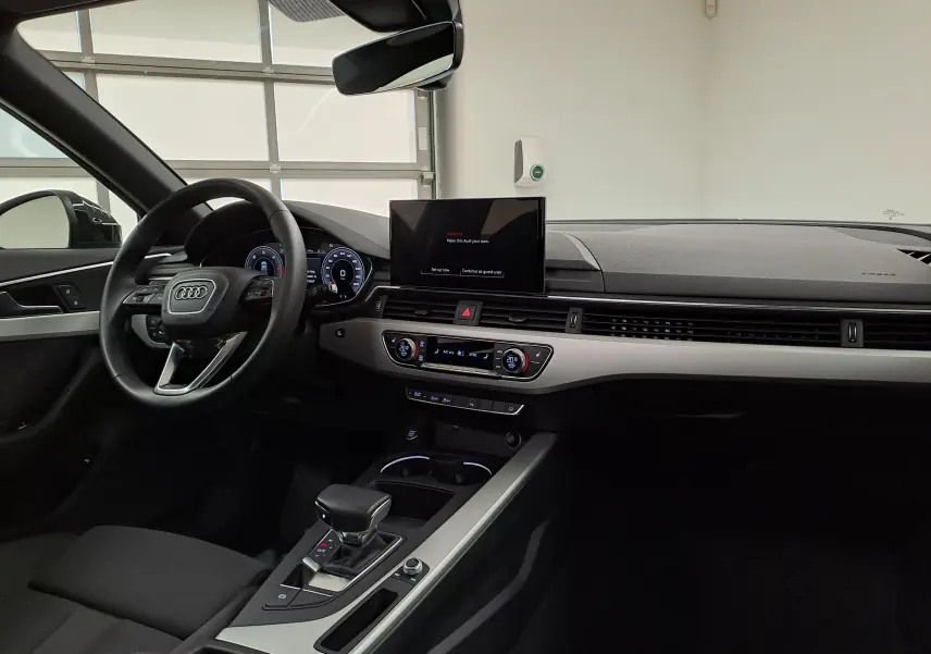 Intérieur de l'Audi A4 Avant 40 TDI 2024 vu côté conducteur, tableau de bord moderne et écran central allumé.