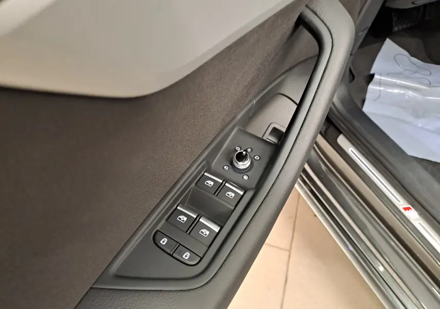 Gros plan sur les commandes de lève-vitres et rétroviseurs côté conducteur de l'Audi A4 Avant Gris Daytona 2024.