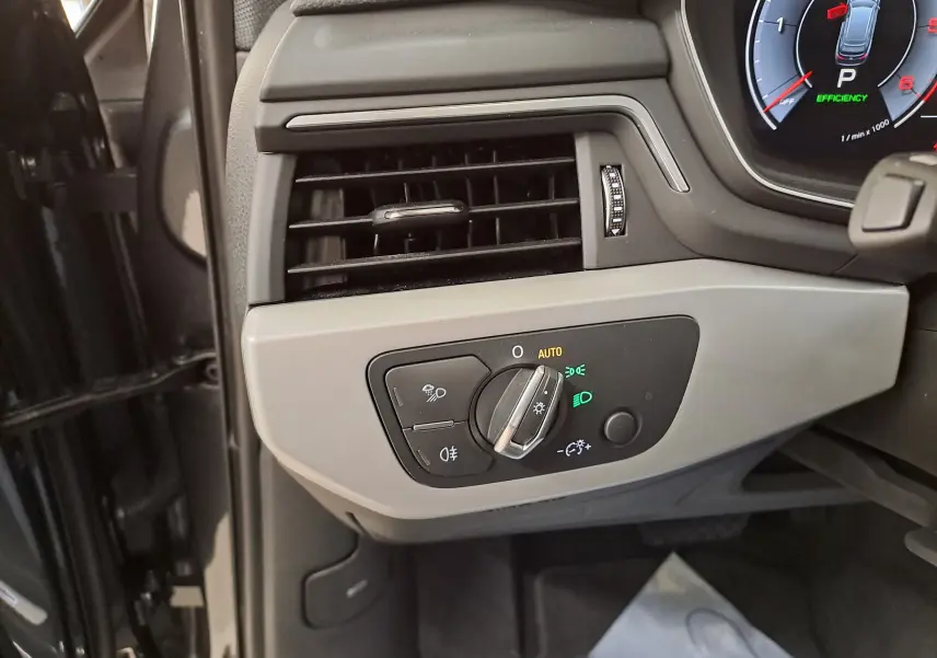 Gros plan sur la commande des feux à gauche du tableau de bord de l'Audi A4 Avant gris Daytona 2024